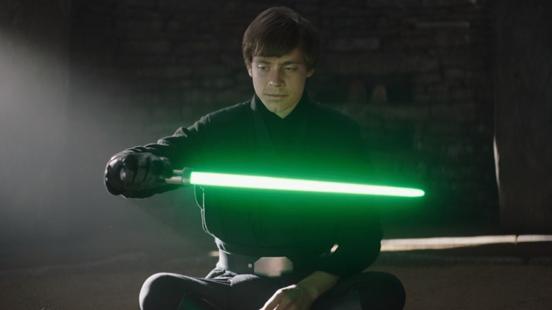 Luke Skywalker holds Yoda's lightsaber